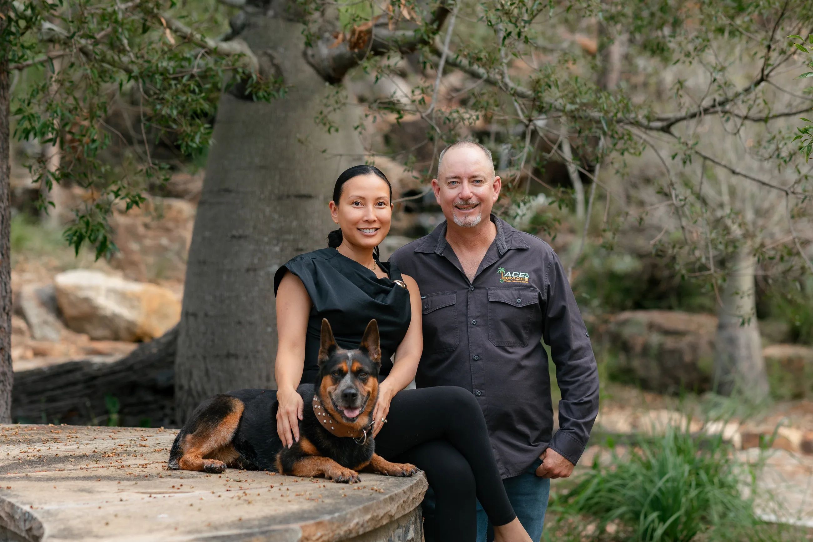 Russell and Aimee Clark with Ace the dog, sitting in front of a giant bottle tree